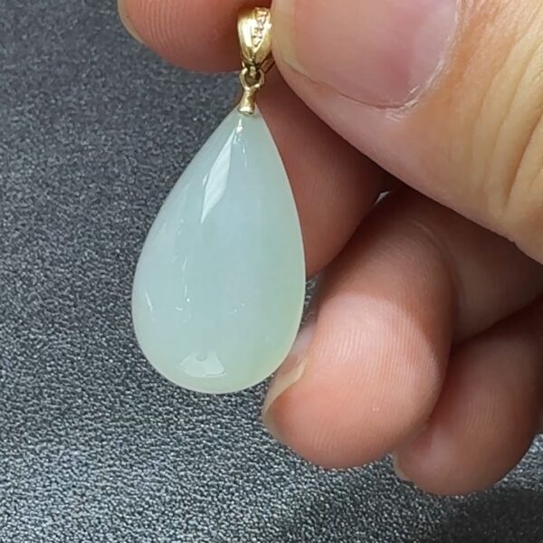 直播貨品編號 #338 的18K鑲嵌白色水滴吊墜,外型如初雪凝露,展現簡潔雅致的高冷美感。水滴造型柔和靈動,寓意純淨心念與堅韌精神;白色翡翠質地通透細膩,在燈光映照下泛出柔潤光澤,猶如心湖微波,靜中藏韻。周邊由18K金優雅包邊,線條流暢,既穩固又增添光澤,完美融合古典玉石與現代設計。