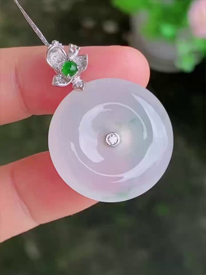 【滿祿翡翠】18K白金花頭翡翠平安扣 | 白冰清透、乾淨水頭好吊墜 (附權威鑑定證書) 1 本品尺寸為 22.3 × 6.2mm,種水與色澤表現卓越。工藝細節方面,這件白色翡翠平安扣的玉水頭很好,種質細膩,質地極為乾淨,在微光下呈現出瑩潤如脂、起冰浮光的優質底色。匠人精心考究比例,將扣身打磨得飽滿對稱,線條流暢流暢。上方的 18K 白金花頭設計扣頭工藝極其細緻,花瓣線條生動立體,與結構穩固的白金鑲嵌緊密契合,既完美保護了嬌貴的翡翠,又極大地提升了高級珠寶的層次感。本品隨貨附送權威的香港翡翠鑑定證書,確保天然品質,讓您安心收藏。